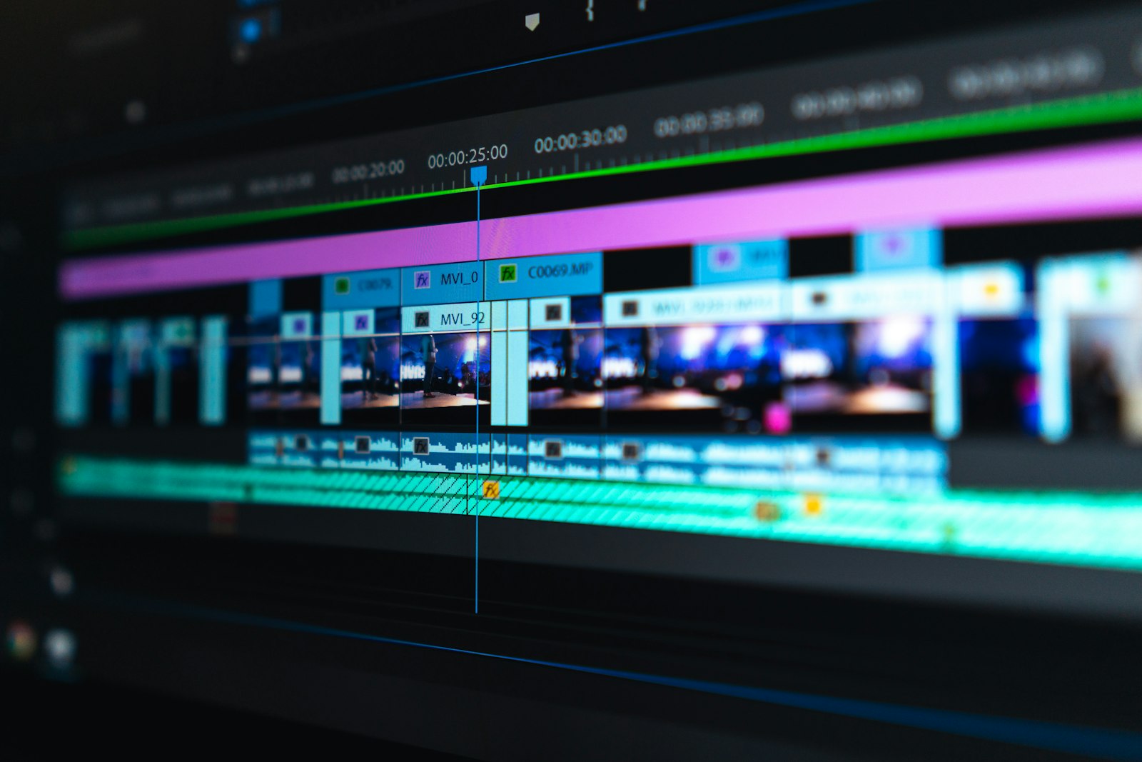 A video editing timeline with colour-coded clips on a monitor