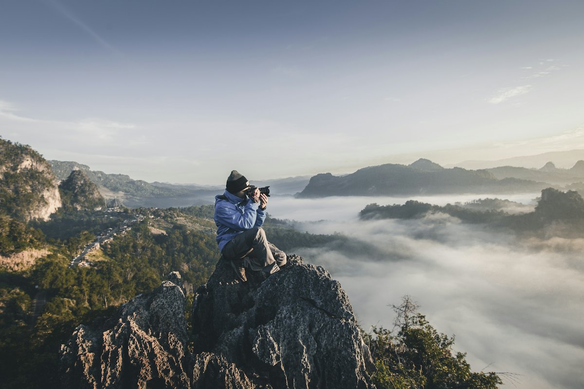 A creator filming on a mountain ridge above the clouds
